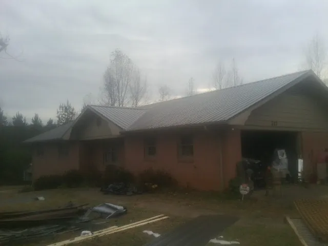 Gray metal roof on a stucco house with an attached garage in Norwood